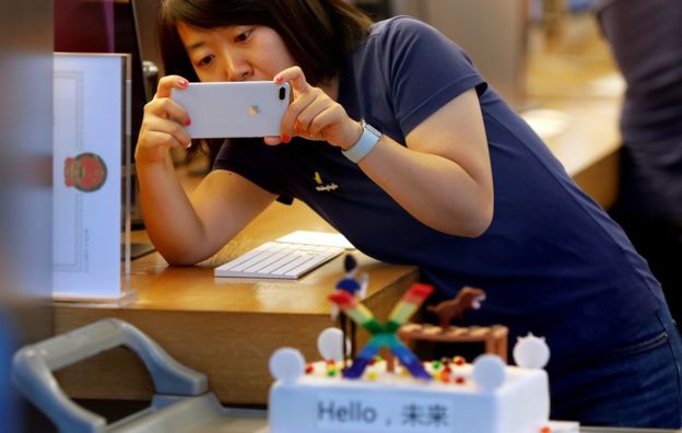 A member of Apple staff takes pictures as new iPhone X begins to sell at an Apple Store in Beijing