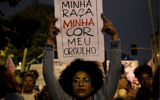 A demonstrator holds a sign during a protest by black women against racism and machismo, 25 July 2018